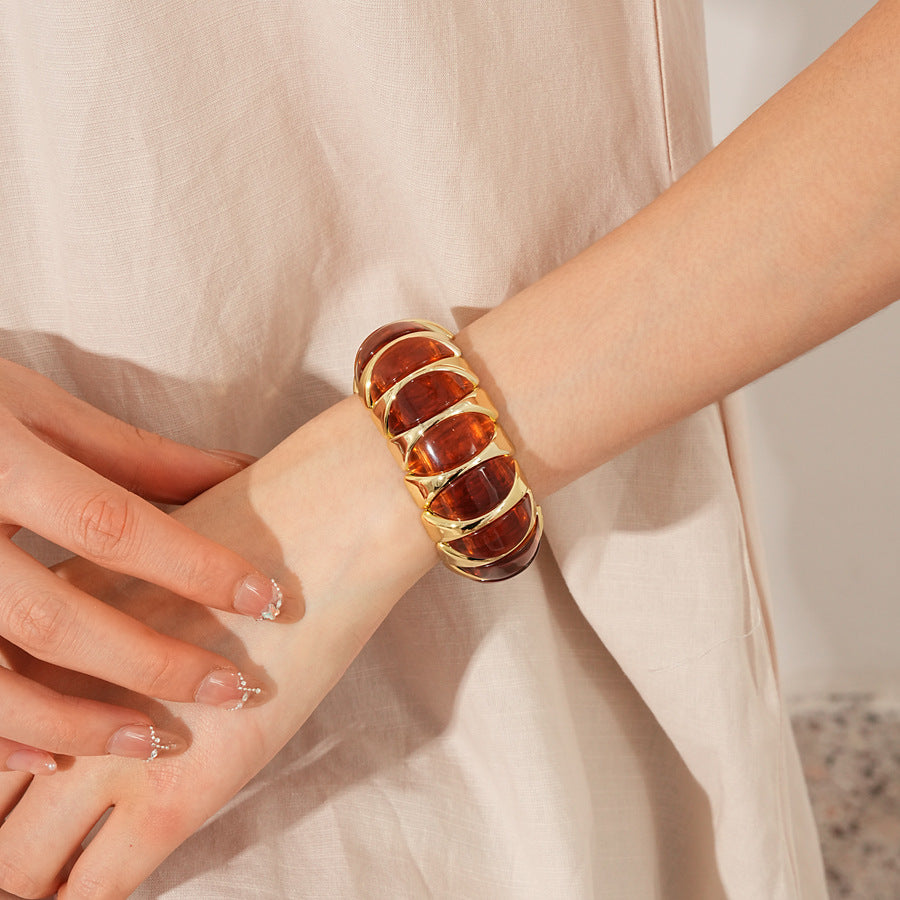 Gold-tone segmented bangle with marbled acrylic dome tiles — Gilded Capsule Resin Bangle.