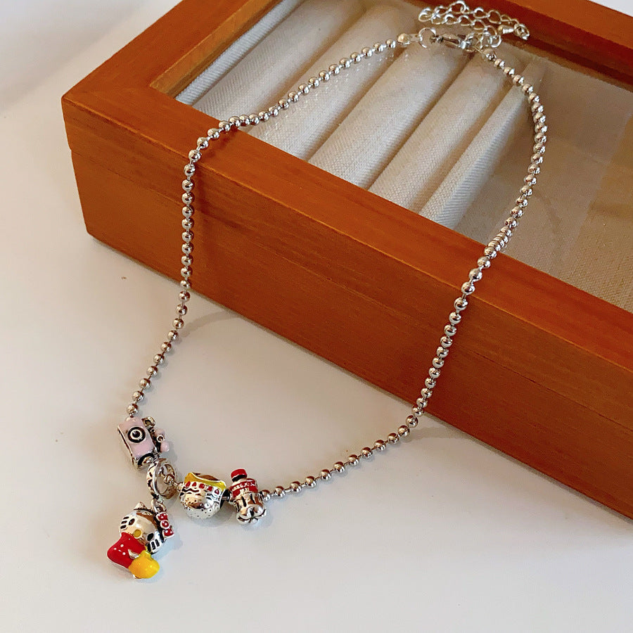 City Voyager Cat Charm Necklace — silver-tone ball chain with enamel cat and camera charms, travel-inspired charm cluster on black pouch