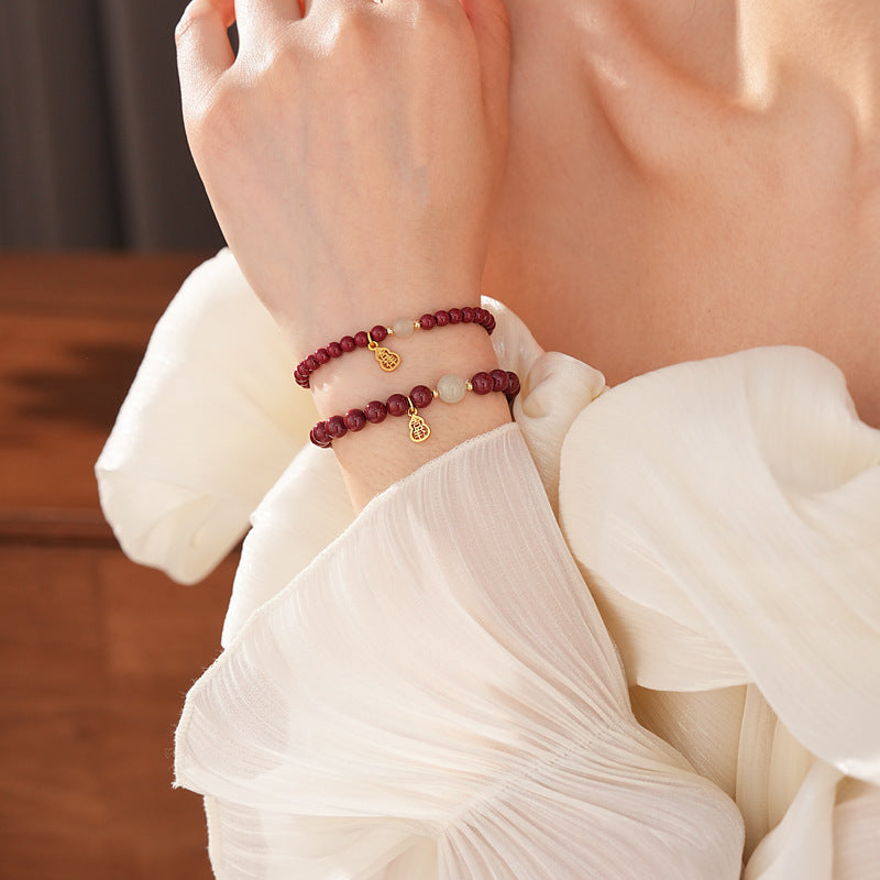 Red cinnabar beaded bracelet with Hetian jade bead and a gold-tone gourd charm.
