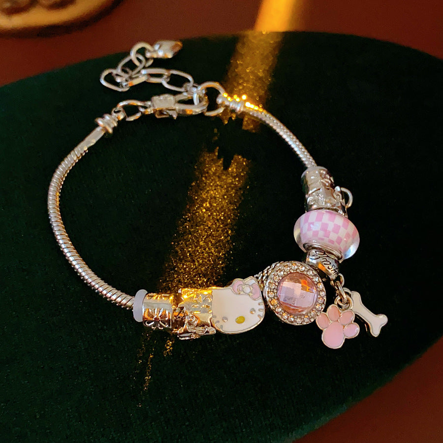 Rosy Pawprints Charm Bracelet — silver-tone snake chain with pink crystal bezel, checker enamel bead, cat-with-bow, paw and bone charms in jewelry tray