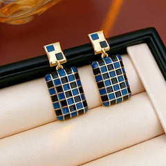 Gilded Mosaic Drop Earrings in two colors — geometric enamel checker tiles with gold-plated frame, Midnight Blue and Mocha Ivory, silver post dangle design on jewelry tray