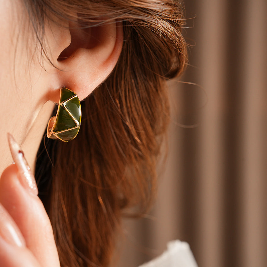 Set of four geometric enamel hoop earrings in white, blue, coffee, and green displayed in a jewelry tray