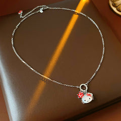 Silver-tone necklace with a cute cat face charm, red bow, red flower and clover accents; copper base with zircon details; 52 cm chain, 1.6 cm pendant, displayed on a black jewelry pad.