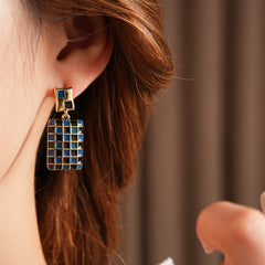 Gilded Mosaic Drop Earrings in two colors — geometric enamel checker tiles with gold-plated frame, Midnight Blue and Mocha Ivory, silver post dangle design on jewelry tray