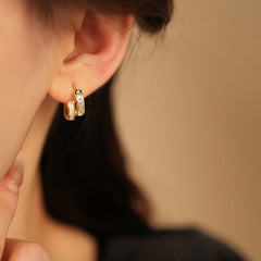 Gold huggie hoop earrings with ivory enamel arc and baguette CZ row — Luna Arc Enamel Baguette Huggies.