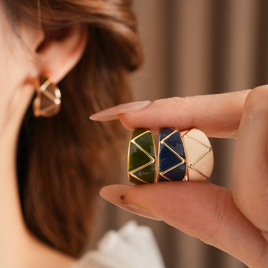 Set of four geometric enamel hoop earrings in white, blue, coffee, and green displayed in a jewelry tray
