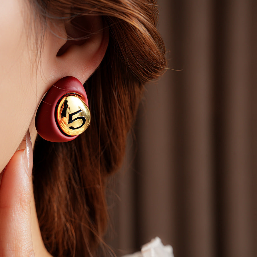 Matte pebble stud earrings with mirrored gold dome engraved with 5 — in white, black, coffee, and red — Gilded Numeral 5 Pebble Studs.