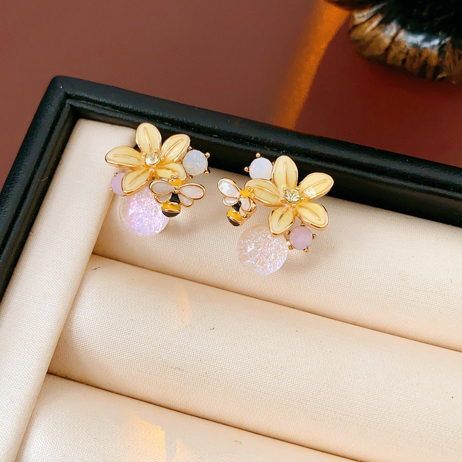 Honeybee Blossom Crystal Stud Earrings — gold flower studs with tiny bee charm and pink crystal orb on black jewelry box