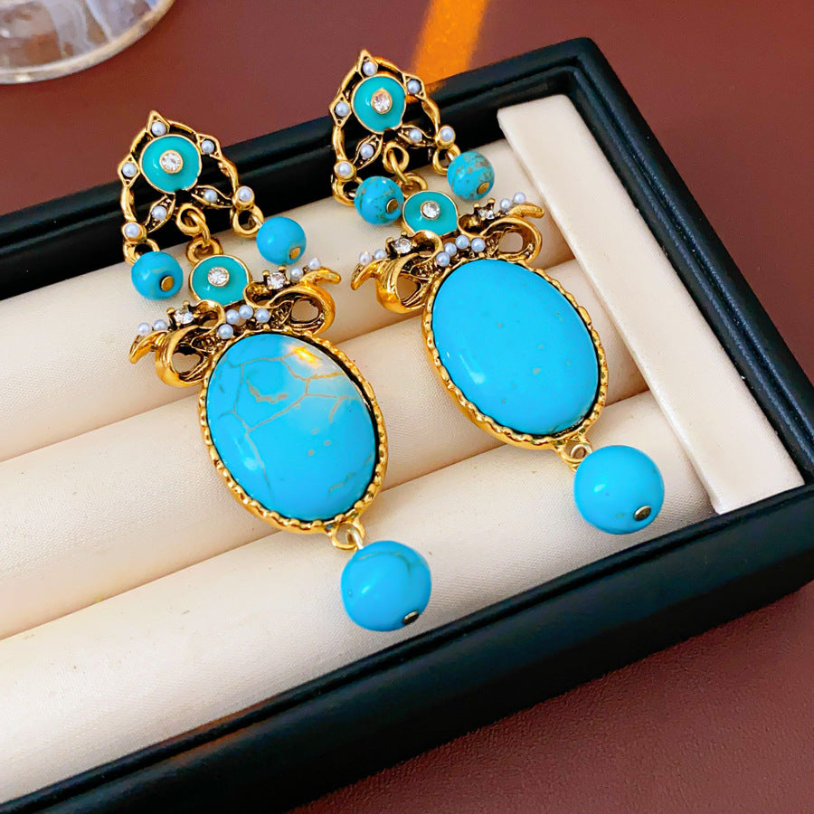 Gold filigree earrings with large turquoise cabochons, crystal accents, and dangling bead — Azure Oasis Turquoise Earrings.