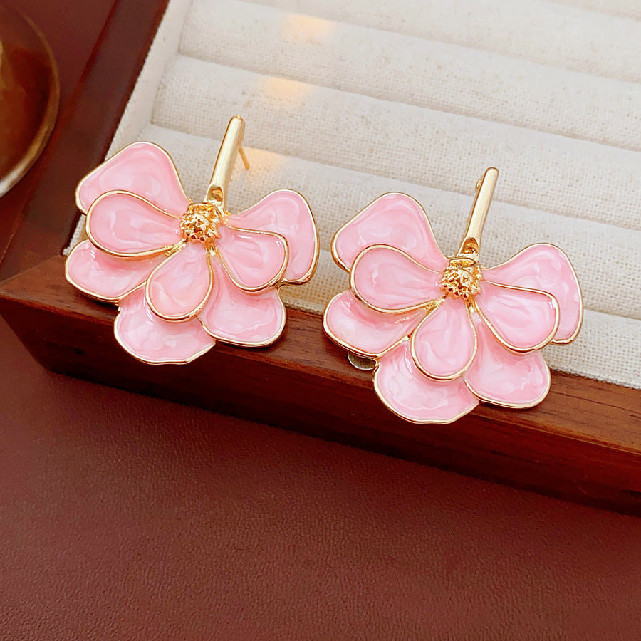 Close-up of pink enamel flower earrings with gold tone petals, statement design on jewelry tray