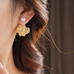 Double-pearl stud earrings with gold-tone butterfly and star charms displayed in a jewelry tray — Double Pearl Charm Studs.