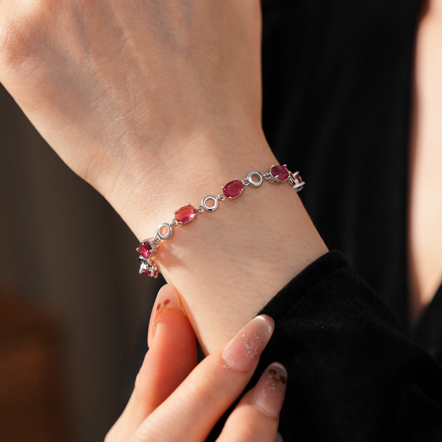 Oval Radiance Zircon Bracelet with silver-tone links and rose zircon stones, displayed on a book background