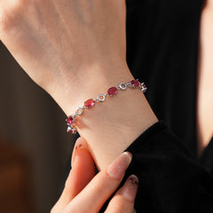 Oval Radiance Zircon Bracelet with silver-tone links and rose zircon stones, displayed on a book background