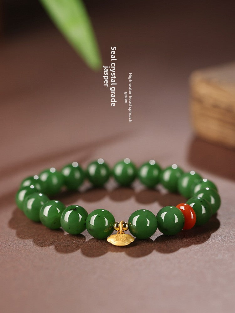 Green Hetian (nephrite) jade bead bracelet with red spacer and gold-tone charm