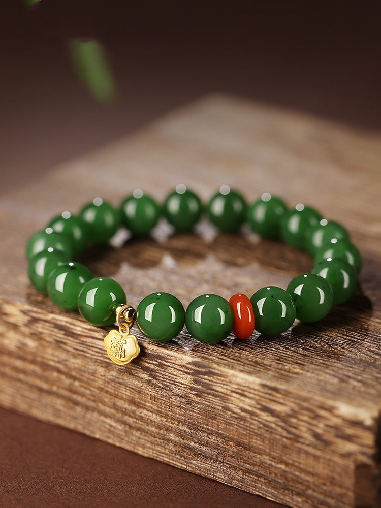 Green Hetian (nephrite) jade bead bracelet with red spacer and gold-tone charm