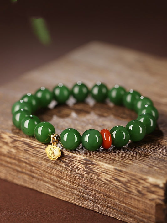 Green Hetian (nephrite) jade bead bracelet with red spacer and gold-tone charm
