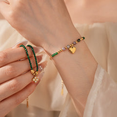 Two variant options of a malachite charm bracelet: beaded green strand with a crystal bloom charm, and a gold-tone chain with malachite accents and a heart pendant — Malachite Charm Bracelet (Variants).
