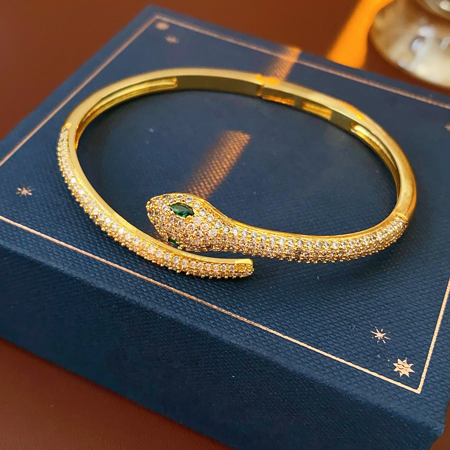 Gold and silver snake-shaped zircon bangles with emerald eyes — Serpent Luxe Bangle by Glazenya.