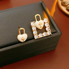 Enamel heart-lock and rhinestone square padlock mismatched stud earrings in gold tone.