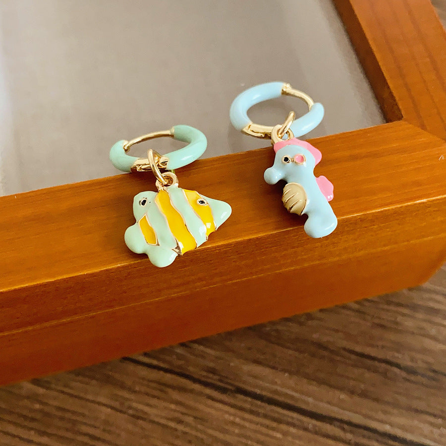Pastel enamel huggie earrings with mismatched seahorse and striped fish charms — Seafoam Mismatch Ocean Charm Huggies.
