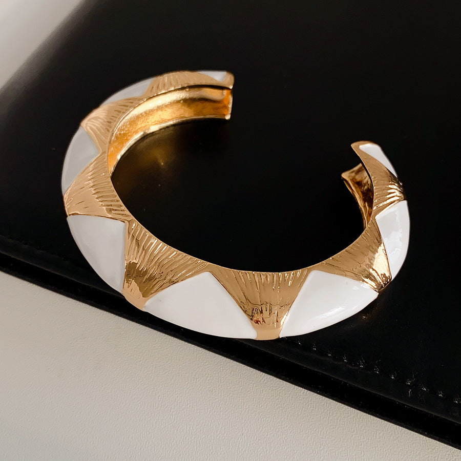 Gold-tone open cuff with triangular glossy enamel peaks; three variants (black, white, red) — Harlequin Enamel Cuff.