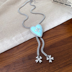Lariat necklace with beaded-edge heart pendant and twin tassel blossoms on model — Regal Heart Tassel Lariat Necklace.