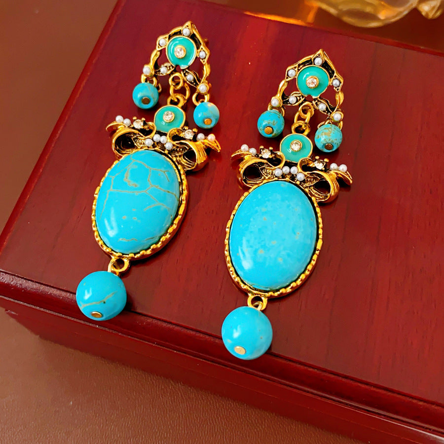 Gold filigree earrings with large turquoise cabochons, crystal accents, and dangling bead — Azure Oasis Turquoise Earrings.