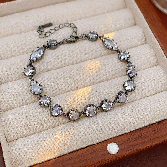 Midnight Sparkle Bracelet with round and pear-cut zircons set in noir metal, adjustable chain