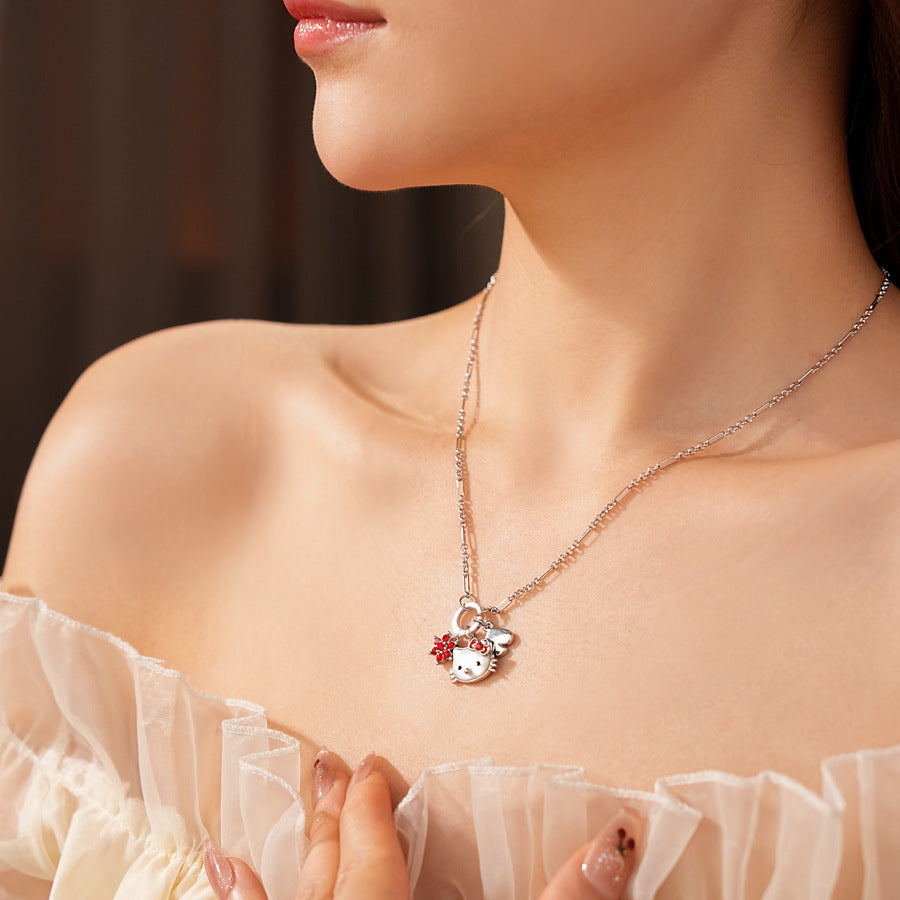 Silver-tone necklace with a cute cat face charm, red bow, red flower and clover accents; copper base with zircon details; 52 cm chain, 1.6 cm pendant, displayed on a black jewelry pad.