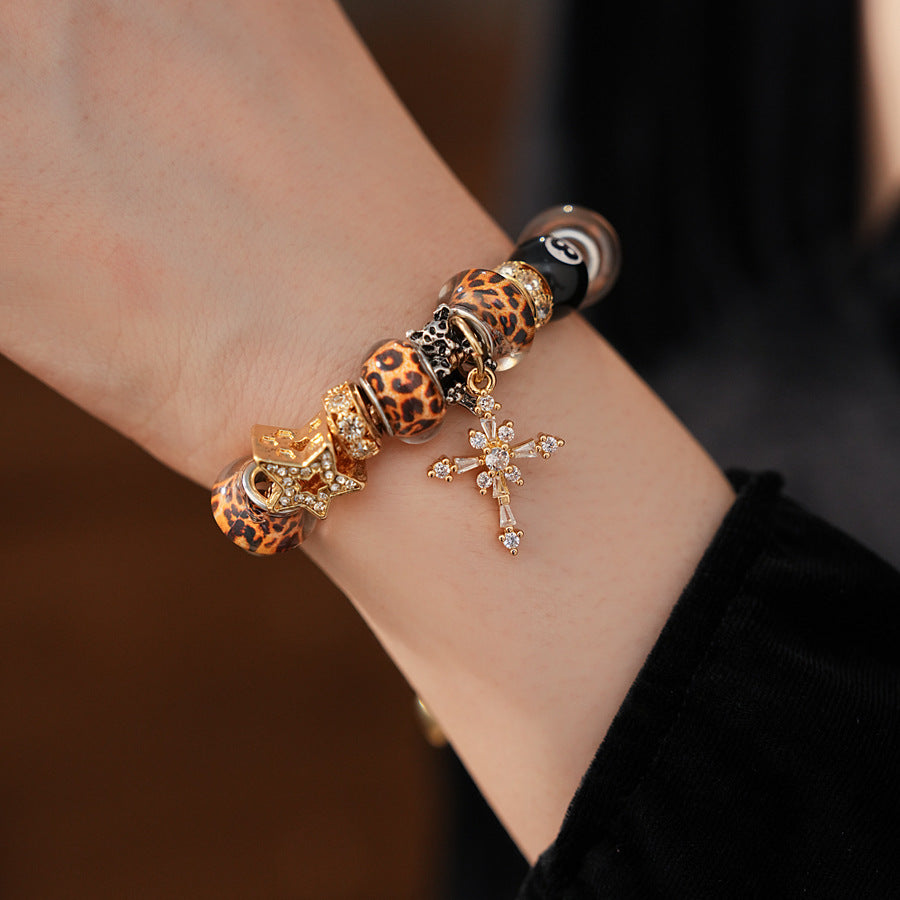 Leopard Cross Luxe Bracelet with leopard-patterned beads, zircon accents, black 8-ball bead, and cross pendant on gold chain