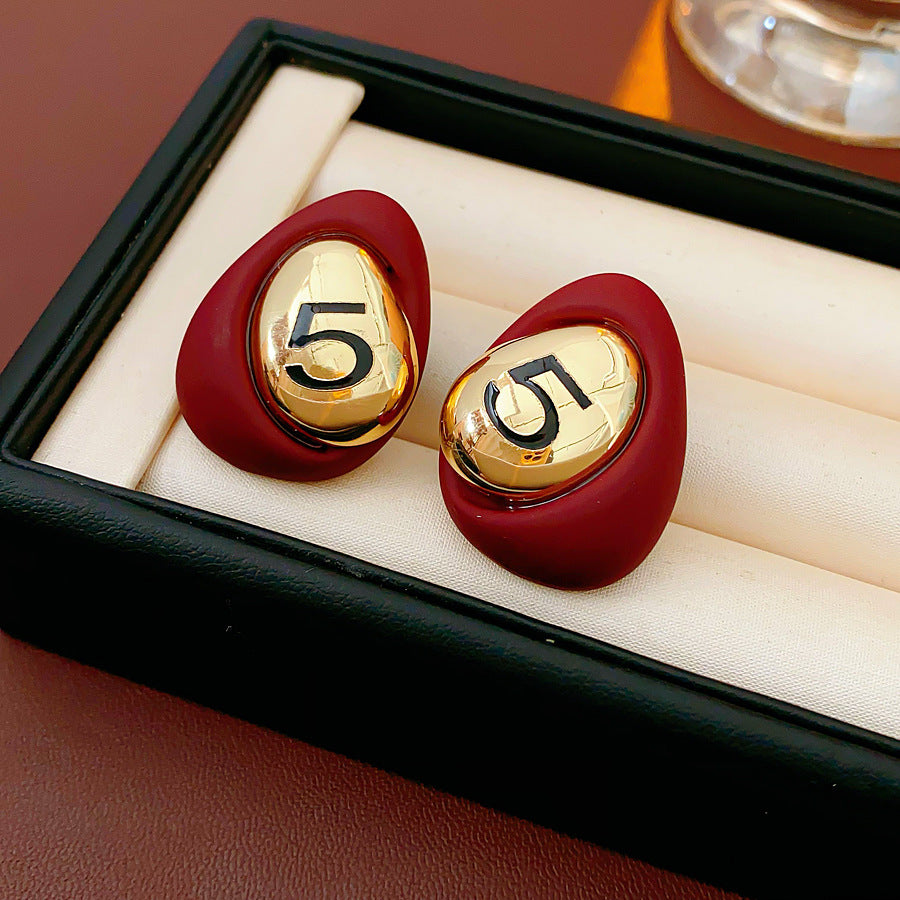 Matte pebble stud earrings with mirrored gold dome engraved with 5 — in white, black, coffee, and red — Gilded Numeral 5 Pebble Studs.