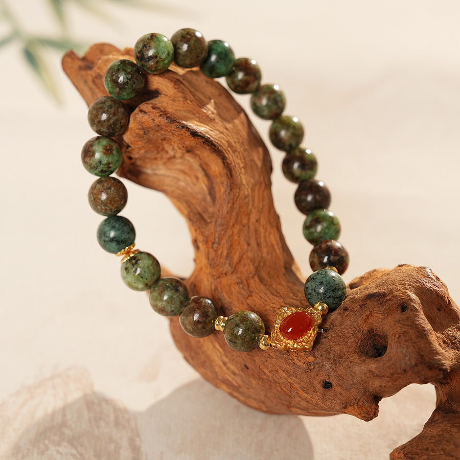<div class="gz-desc">
  <p>Earthy and refined <strong>natural stone bracelet</strong> combining lush <strong>green ghost</strong> beads with smooth <strong>agate</strong>, accented by a warm red centerpiece and gold-tone spacers for a subtle touch of luxury.</p>

  <h3>Design Story</h3>
  <p>The <strong>Forest Ember Agate Bracelet</strong> evokes the calm of an ancient forest lit by a single ember. Mossy green tones bring grounding energy, while the red accent adds a gentle spark—balance between serenity an
