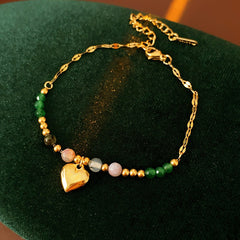 Two variant options of a malachite charm bracelet: beaded green strand with a crystal bloom charm, and a gold-tone chain with malachite accents and a heart pendant — Malachite Charm Bracelet (Variants).