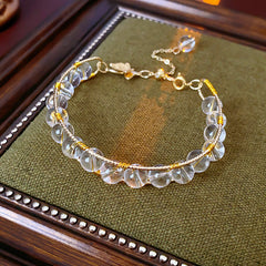 Natural stone beaded bracelets in multiple colors including red agate, rose quartz, and white crystal, with golden accents displayed in a jewelry tray.