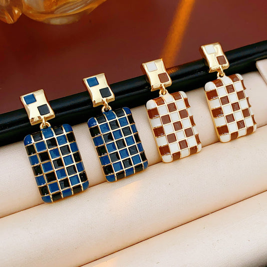 Gilded Mosaic Drop Earrings in two colors — geometric enamel checker tiles with gold-plated frame, Midnight Blue and Mocha Ivory, silver post dangle design on jewelry tray