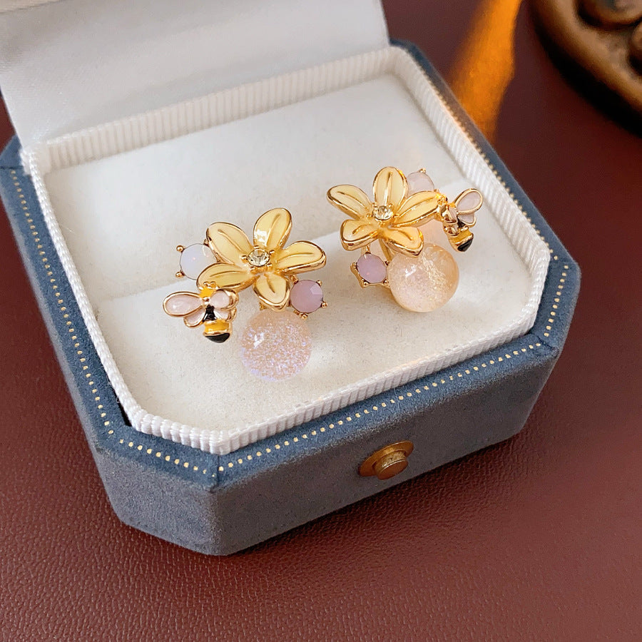 Honeybee Blossom Crystal Stud Earrings — gold flower studs with tiny bee charm and pink crystal orb on black jewelry box