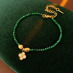Two variant options of a malachite charm bracelet: beaded green strand with a crystal bloom charm, and a gold-tone chain with malachite accents and a heart pendant — Malachite Charm Bracelet (Variants).