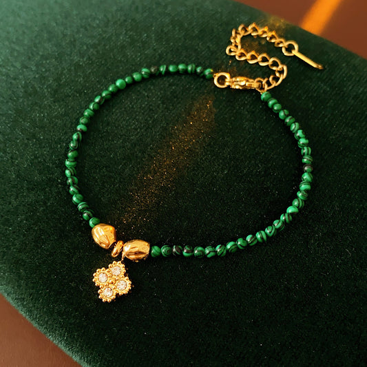 Two variant options of a malachite charm bracelet: beaded green strand with a crystal bloom charm, and a gold-tone chain with malachite accents and a heart pendant — Malachite Charm Bracelet (Variants).