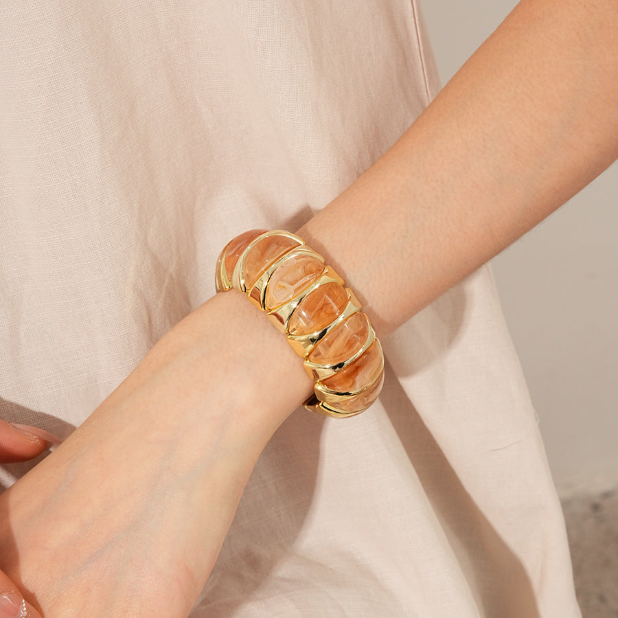 Gold-tone segmented bangle with marbled acrylic dome tiles — Gilded Capsule Resin Bangle.