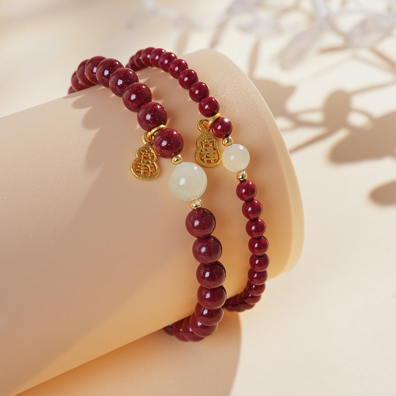 Red cinnabar beaded bracelet with Hetian jade bead and a gold-tone gourd charm.