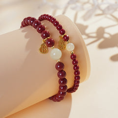 Red cinnabar beaded bracelet with Hetian jade bead and a gold-tone gourd charm.