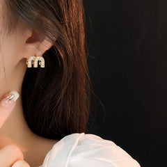 Gold arc “M” stud earrings in pavé crystal and white enamel — Muse Arc Pavé Stud Earrings.