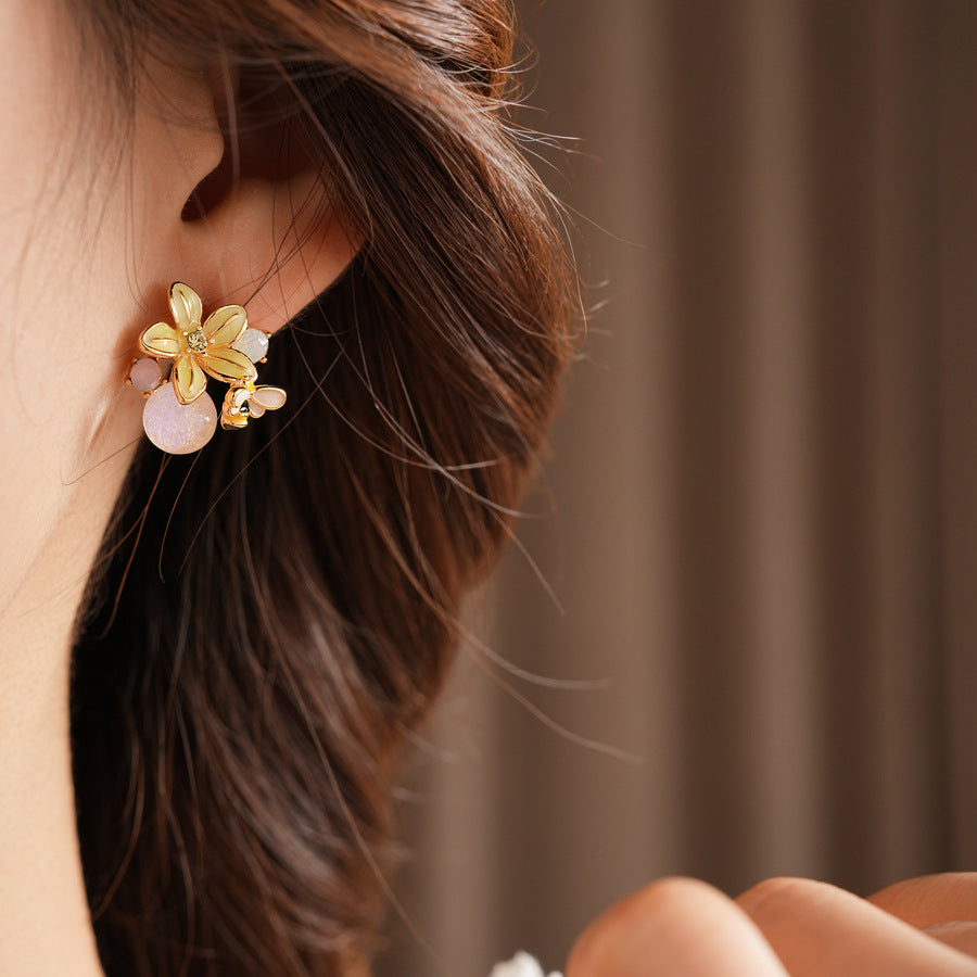 Honeybee Blossom Crystal Stud Earrings — gold flower studs with tiny bee charm and pink crystal orb on black jewelry box