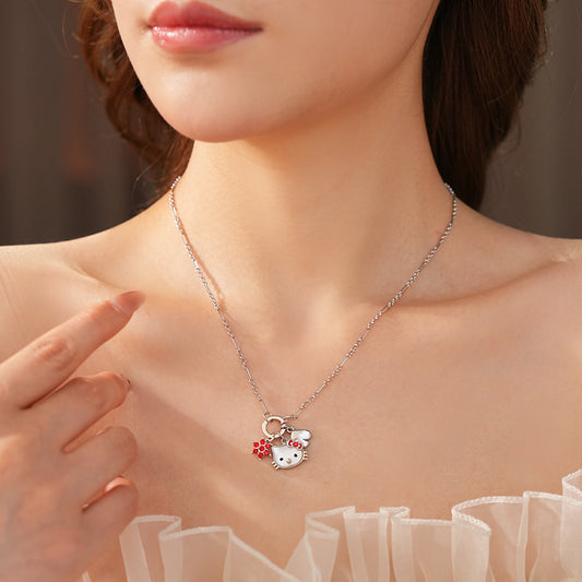 Silver-tone necklace with a cute cat face charm, red bow, red flower and clover accents; copper base with zircon details; 52 cm chain, 1.6 cm pendant, displayed on a black jewelry pad.