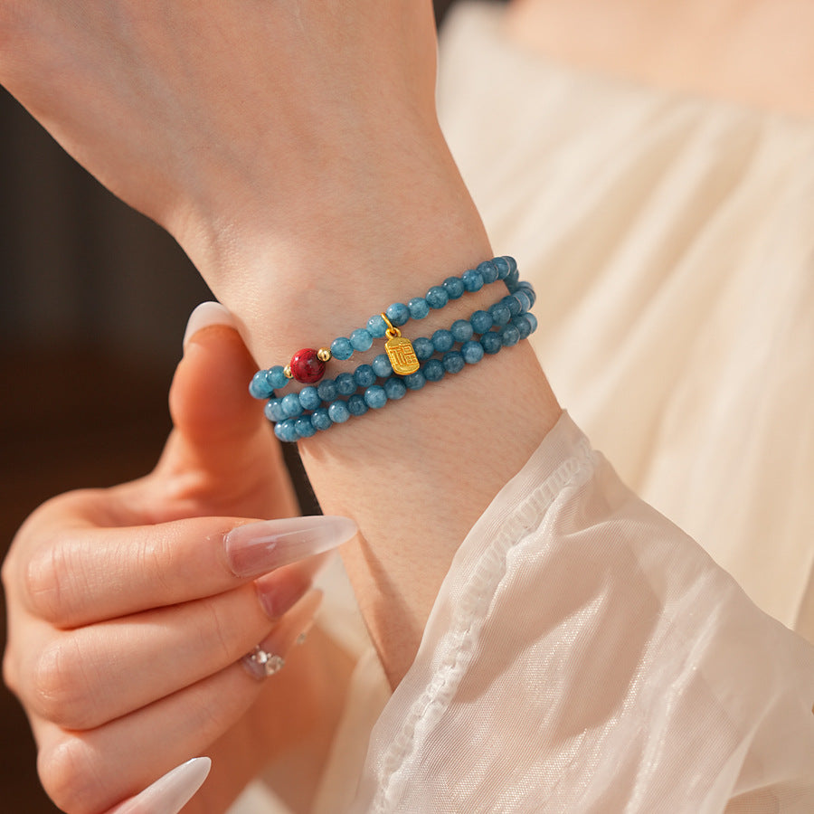 Blue multi-wrap beaded bracelet with red accent bead and gold charm — Azure Charm Wrap Bracelet.