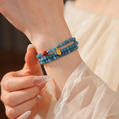 Blue multi-wrap beaded bracelet with red accent bead and gold charm — Azure Charm Wrap Bracelet.