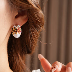 Enamel masquerade face stud earrings with red and black halves and gold filigree on a velvet jewelry box — Venetian Masquerade Studs.