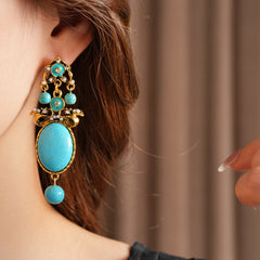 Gold filigree earrings with large turquoise cabochons, crystal accents, and dangling bead — Azure Oasis Turquoise Earrings.