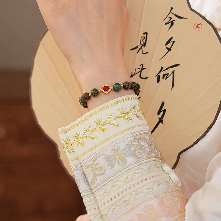 <div class="gz-desc">
  <p>Earthy and refined <strong>natural stone bracelet</strong> combining lush <strong>green ghost</strong> beads with smooth <strong>agate</strong>, accented by a warm red centerpiece and gold-tone spacers for a subtle touch of luxury.</p>

  <h3>Design Story</h3>
  <p>The <strong>Forest Ember Agate Bracelet</strong> evokes the calm of an ancient forest lit by a single ember. Mossy green tones bring grounding energy, while the red accent adds a gentle spark—balance between serenity an