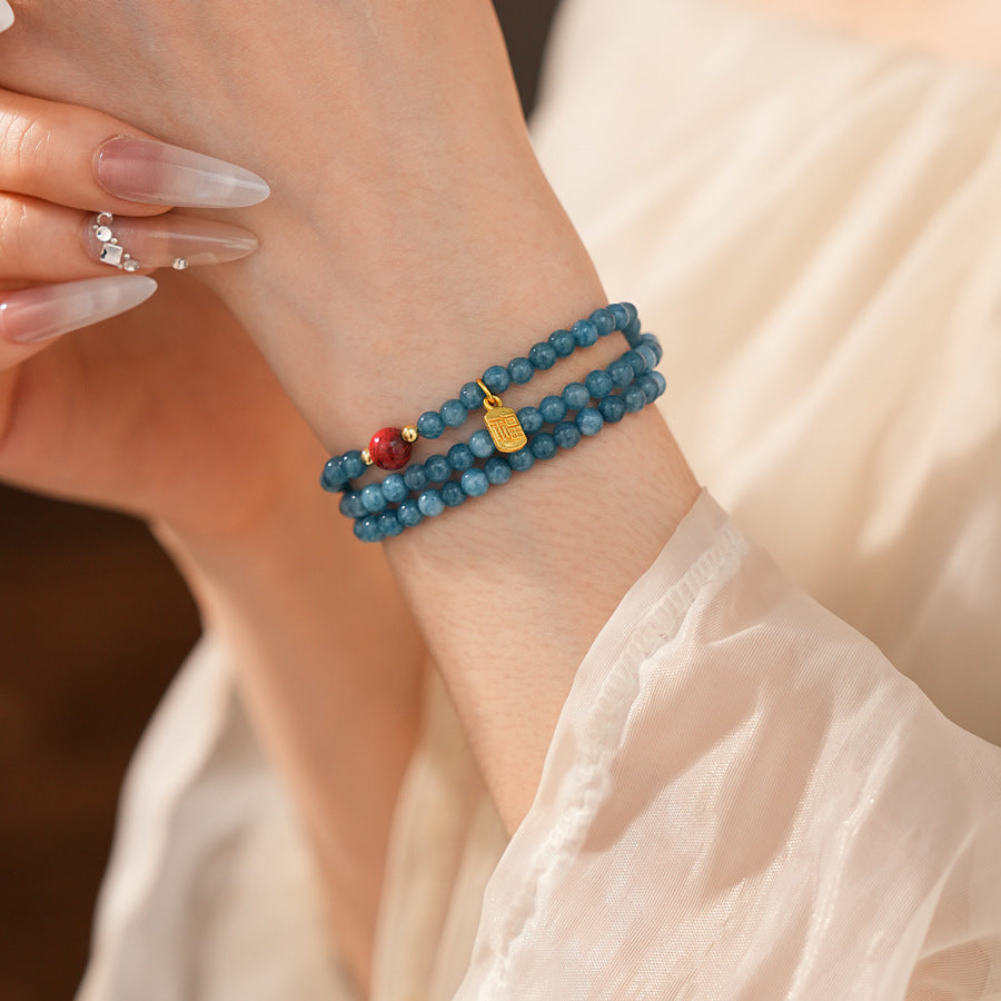 Blue multi-wrap beaded bracelet with red accent bead and gold charm — Azure Charm Wrap Bracelet.